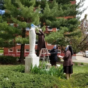 Sisters putting crown on Mary statue outside