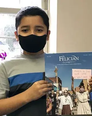 A child holding the Felician Magazine