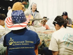 Sister surrounded by teens playing the guitar at NCYC