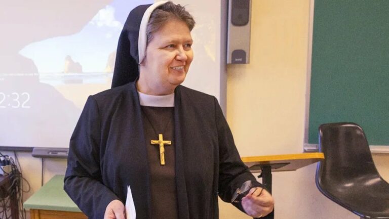 Sr. Mary Honorata Grzeszczuk, wearing her habit, presents in front of a slideshow.