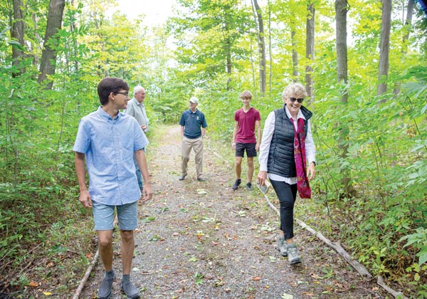 Five people of various ages walk down a wooded path.