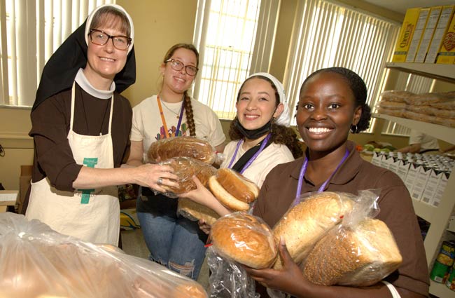 Sister and volunteers gather bread in food pantry.