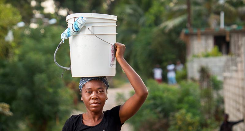 Haitian woman carrying bucket of water on her head